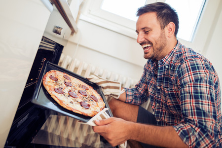 Young man preparing pizza at home.の写真素材