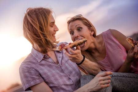 Beautiful young boyfriend  feeding her woman with a slice of pizza.の写真素材