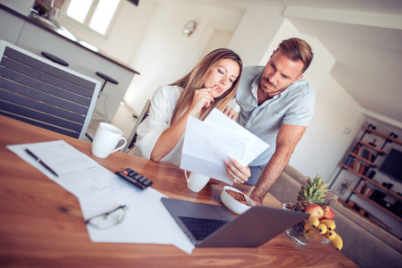 Couple having problem with bills.Worried young couple doing their accounts in the living room.の写真素材