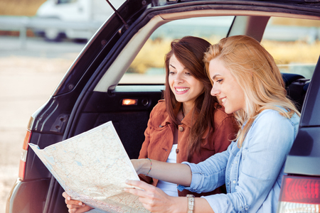 Happy young friends with a map in the car. They are using map on road trip.の写真素材