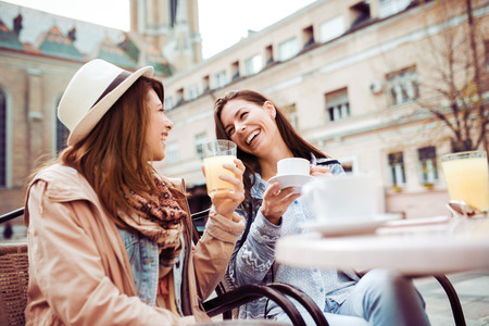 Young female friends dressed casually sitting with coffee.の写真素材