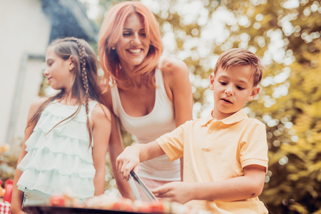 Happy family having a barbecue in their garden in summer.Leisure, food, family and holidays concept.の写真素材
