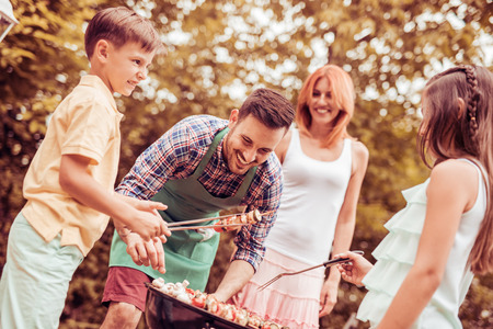 Happy family having a barbecue in their garden in summer.Leisure, food, family and holidays concept.の写真素材