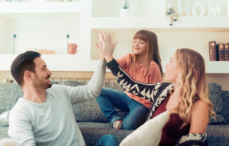 Happy young family having fun with pillows on sofa.