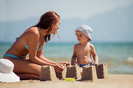 Young beautiful mother and her son having fun on the beach.の写真素材