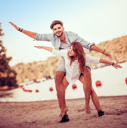 Picture of a joyful couple doing piggyback on the beach.Crazy in love.の写真素材