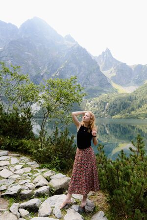 Girl walking a stone path next to a lake with the mountains in the backgroundの写真素材