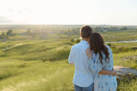 Happy young couple kissing on top of a mountain, with clear sky in the backgroundの写真素材