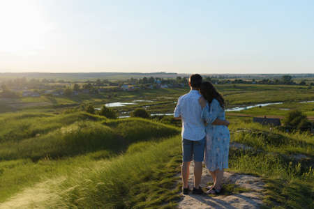 Happy young couple kissing on top of a mountain, with clear sky in the background