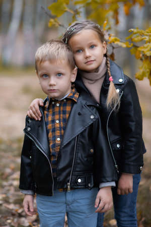 Cute funny smiling little girl and boy are hugging in autumn park. Happy cheerful kidsの写真素材