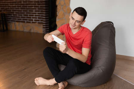 A young gamer man playing video games on smartphone