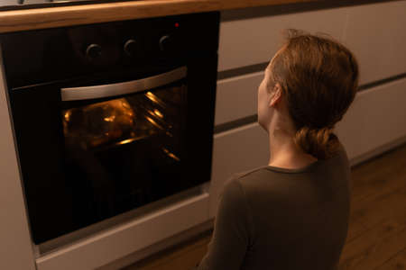 Shot of a girl waiting patiently in front of the ovenの写真素材