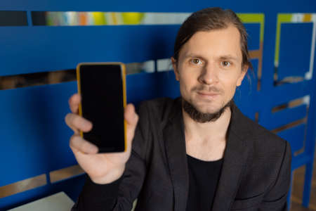 Attractive young man demonstrates the display of his smartphoneの写真素材