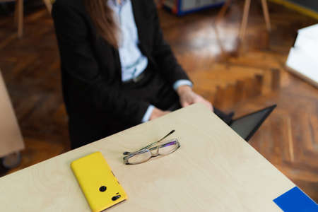 Glasses and a facing-down smartphone on a table.の写真素材