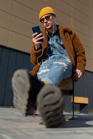 Portrait of young man with earphones and smartphone meditating on bench at daytime. high quality photoの写真素材