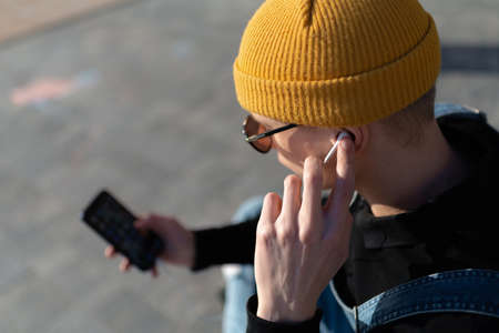 High angle view of man listening to music while using mobile phone. high quality photoの写真素材