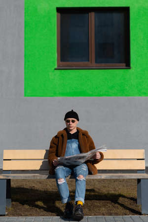 Stylish man is reading a newspaper in front of green window.の写真素材