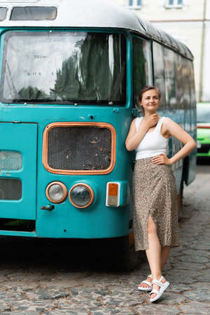 A young woman is standing near a travel bus on the street. street fashion portraitの写真素材
