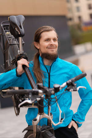 Portrait of a mature man carrying his bicycle on the shoulder. Smiling man carrying the bike in the...