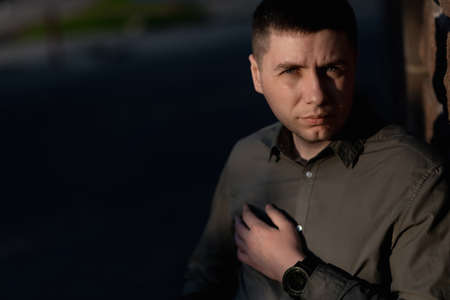 Portrait of the 30-year-old man looking at camera with sun glare on his face. street portrait