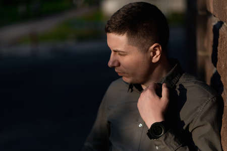 An unhappy man is standing outdoors on a sunny summer day. street portrait