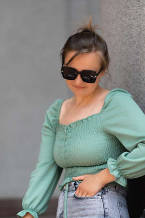 A blonde in sunglasses with a hand in her pocket on the street