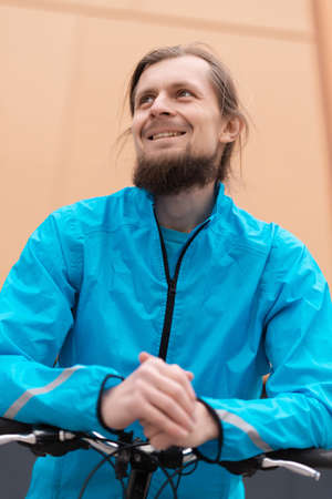 A young man smiling while riding a bicycle on the street