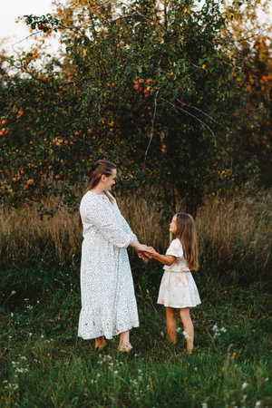 Mother and daughter are dancing in the garden near the apple treeの写真素材