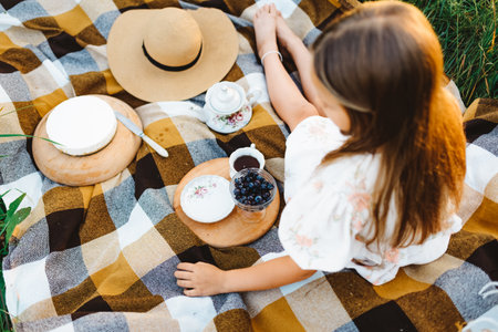 A girl is sitting on a blanket, waiting for her piece of cakeの写真素材