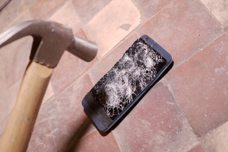 Hammer crash hitting a smartphone, broken touch screen glass slow motion rapid. Shards fragments.の写真素材