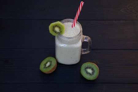 Banana and Kiwi smoothies. Mug jar with smoothie and kiwi on a dark wooden background.の写真素材
