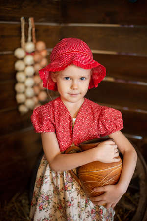 A girl with pies, a little girl in the village on the hay, at her grandmother's in the village, a girl with a basket of pies, children in the village, little red riding hood.の写真素材