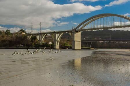 A big bridge with its reflections in the sand and a blue skyの写真素材