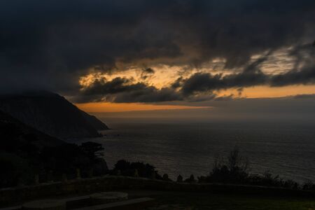 Cliff in the coastline at sunset with yellow colors in the cloudsの写真素材