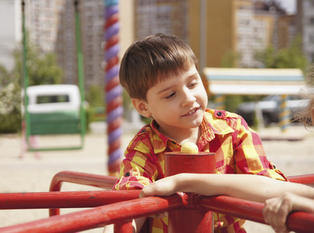 Happy boy with girl riding on a spinning swingの写真素材