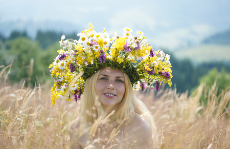 Girl in big wreath on a meadow in grassの写真素材