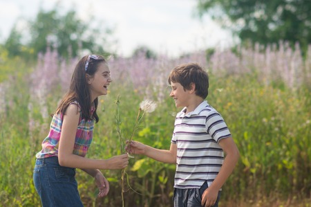 Children blowing dandelion in the green spring grassの写真素材