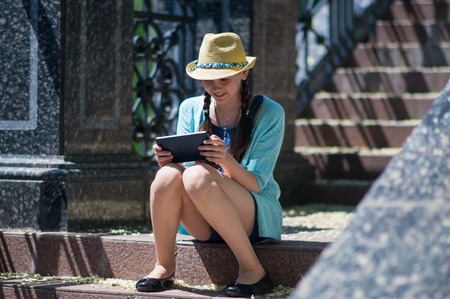 Young girl sitting on the steps with tabletの写真素材