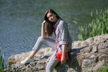 The girl is sitting on the stones near the lakeの写真素材