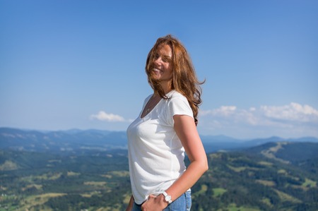 Woman stands in the mountains with hair on her faceの写真素材