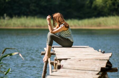 Woman sitting on old wooden bridgeの写真素材