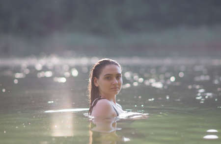 The girl stands in the lake at sunsetの写真素材