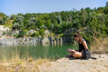 Young girl sitting with a book near the lakeの写真素材