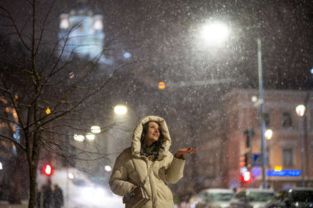 Woman catching snowflakes in the night cityの写真素材