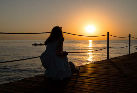 Lonely girl with a cat sits on the pierの写真素材