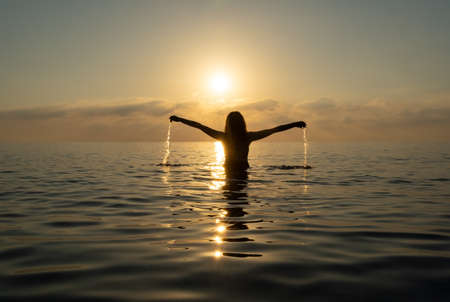 The girl stands in the water and splashesの写真素材