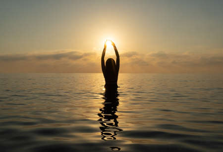 The girl stands in the water and catches the sunの写真素材