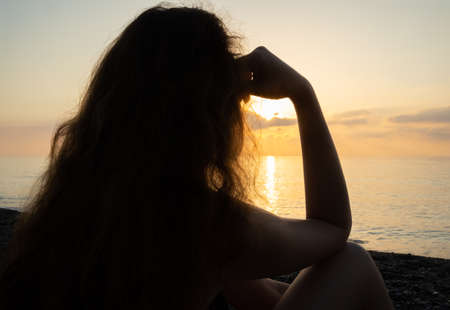 Girl sitting on the beach at dawnの写真素材