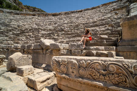 Beautiful girl sits on the ruins of an ancient amphitheaterの写真素材