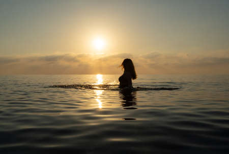 The girl stands in the water and makes wavesの写真素材